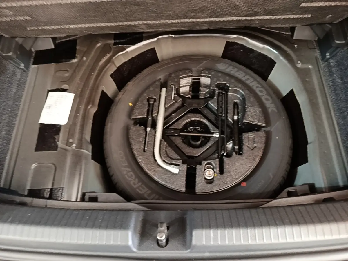 Vue plongeante sur la roue de secours et les outils de bord dans le coffre d'une Volkswagen Polo noire 2020.