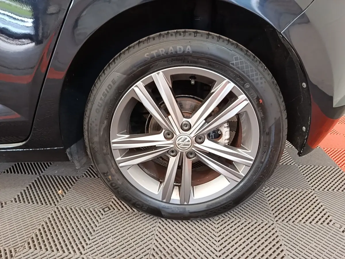 Gros plan sur la roue avant gauche avec jante alliage argentée d'une Volkswagen Polo noire 2020.