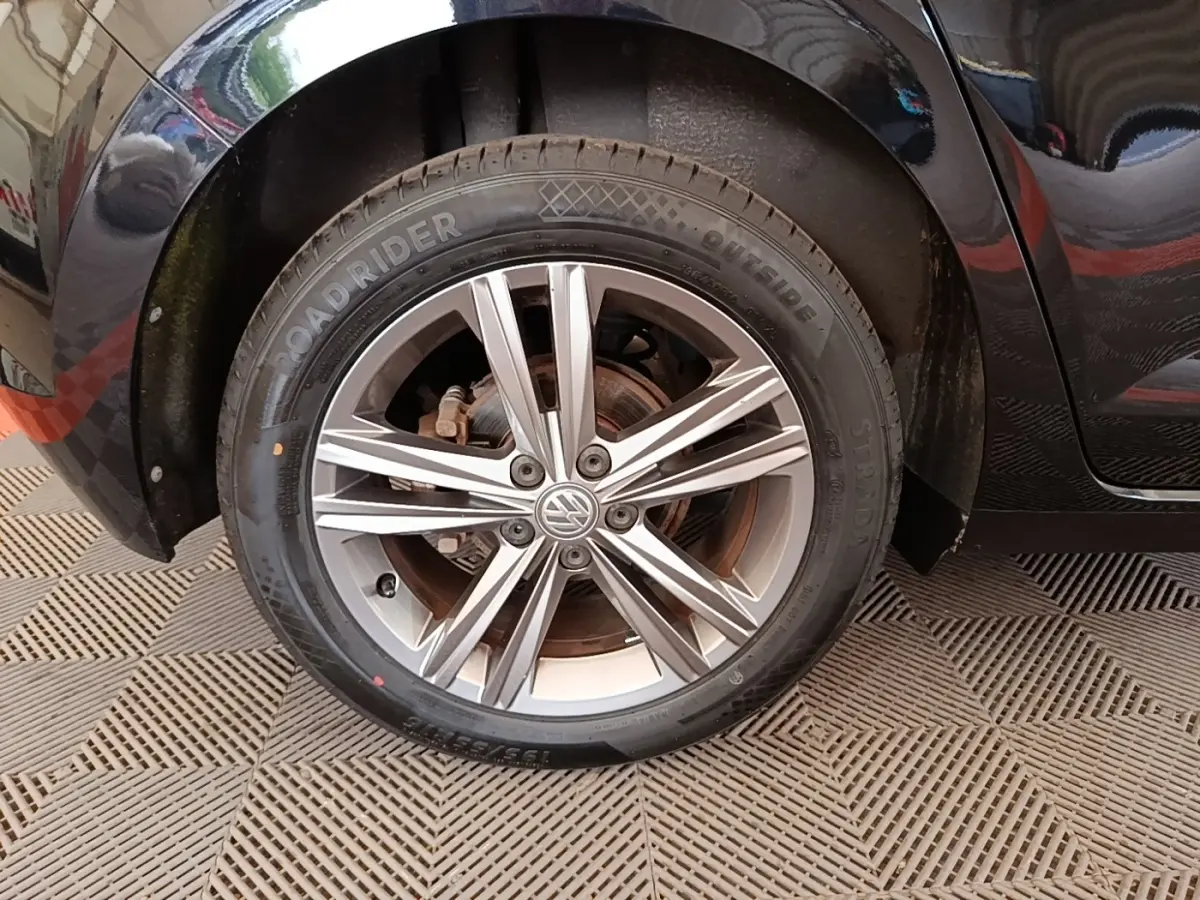 Gros plan sur la roue avant droite d'une Volkswagen Polo noire, mettant en valeur la jante alliage à plusieurs branches.