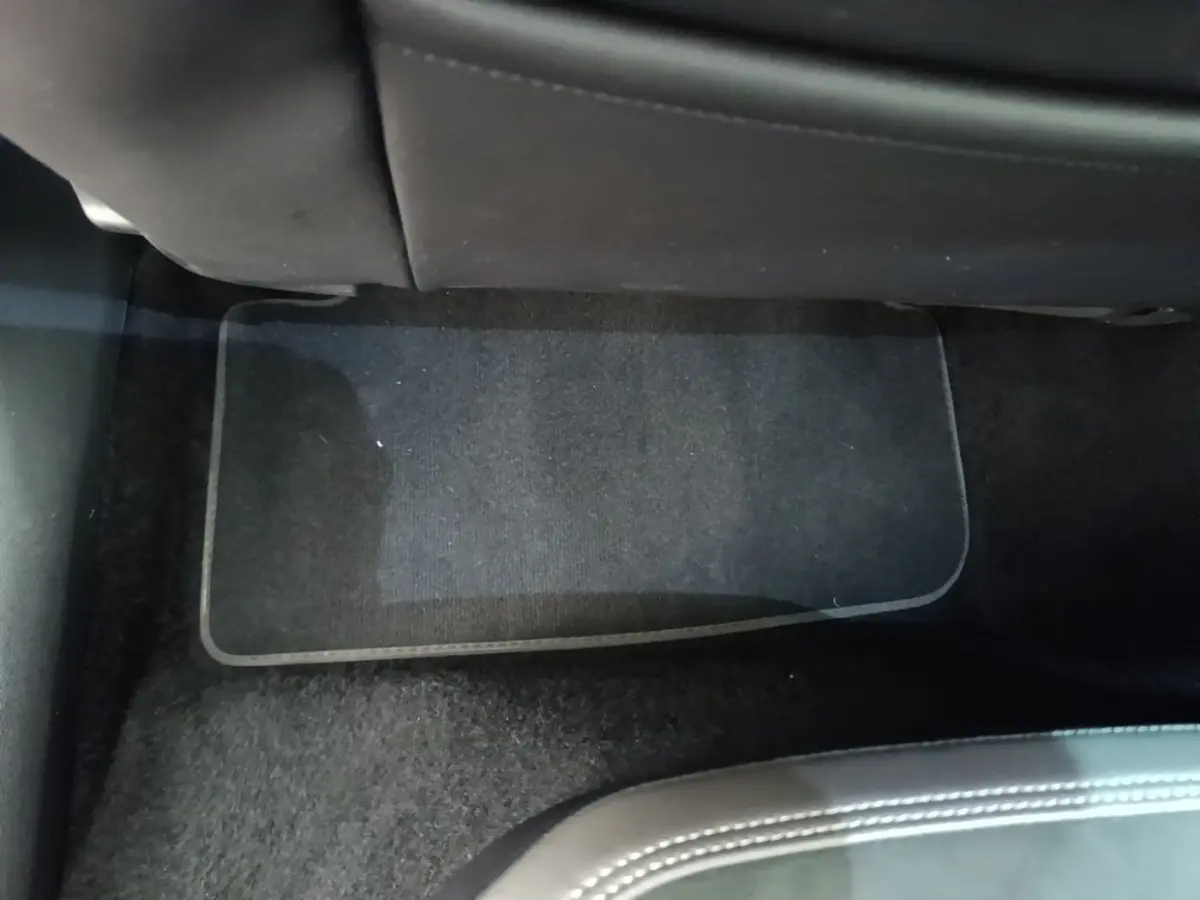 Vue intérieure du plancher arrière côté droit d'une Volkswagen Polo noire, tapis de sol noir visible sous les sièges.