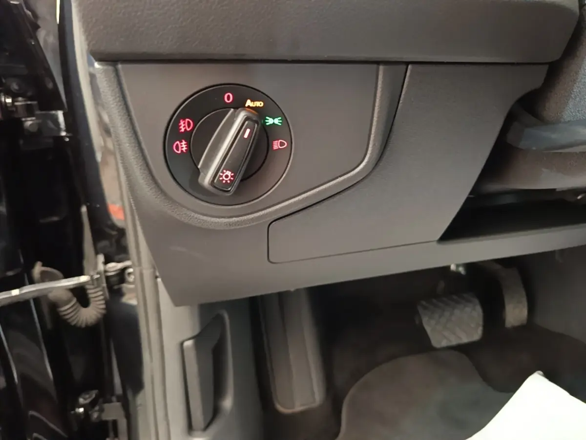 Gros plan sur le bouton de commande des phares dans l'habitacle noir d'une Volkswagen Polo 2020.