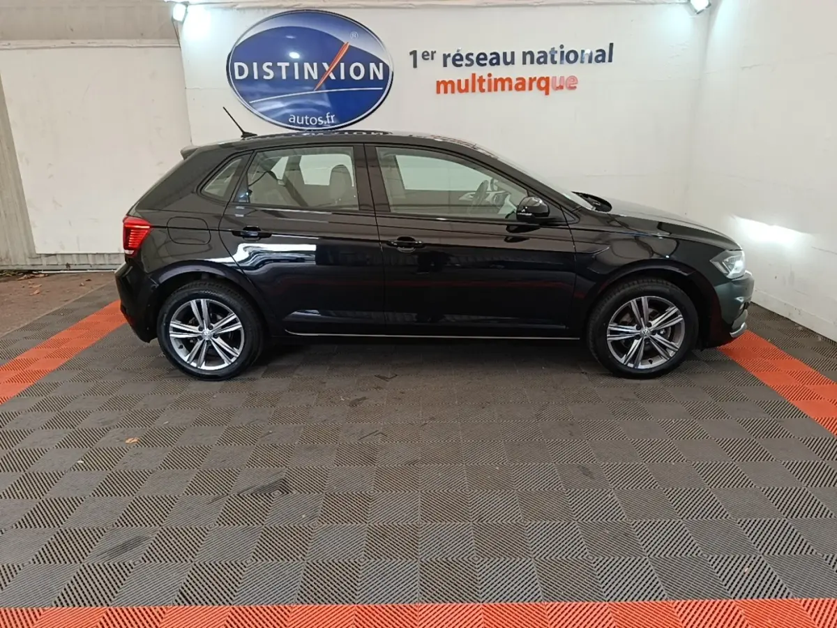 Profil droit d'une Volkswagen Polo noire 2020, avec jantes alliage et vitres teintées, en intérieur showroom.