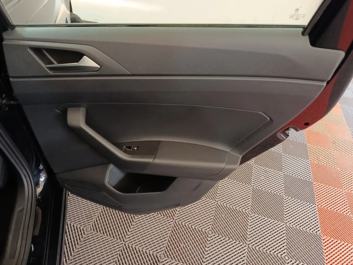 Vue rapprochée de la porte avant gauche noire d’une Volkswagen Polo 1.0 TSI 115 DSG7 Carat avec poignée intégrée.