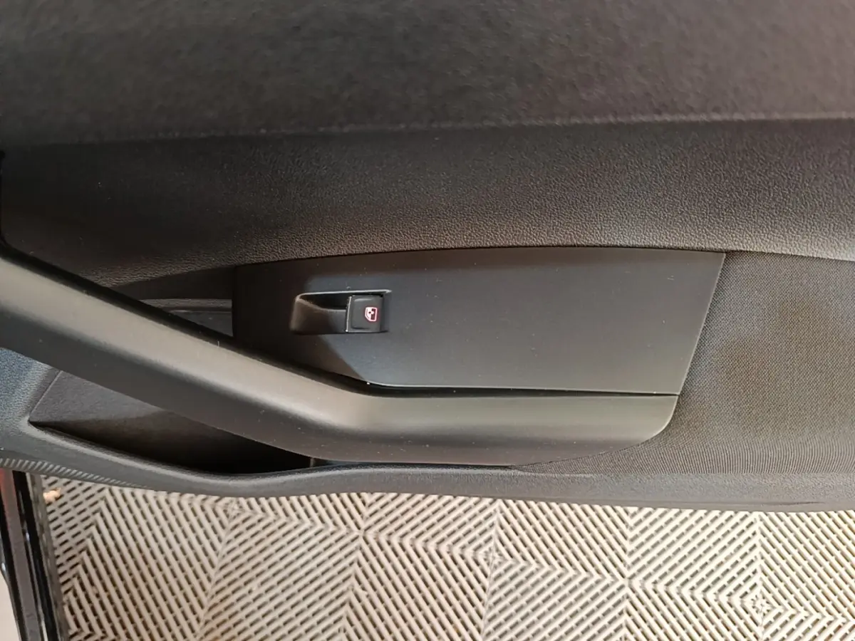 Détail de la poignée intérieure noire de la porte côté gauche d'une Volkswagen Polo noire vue de près.