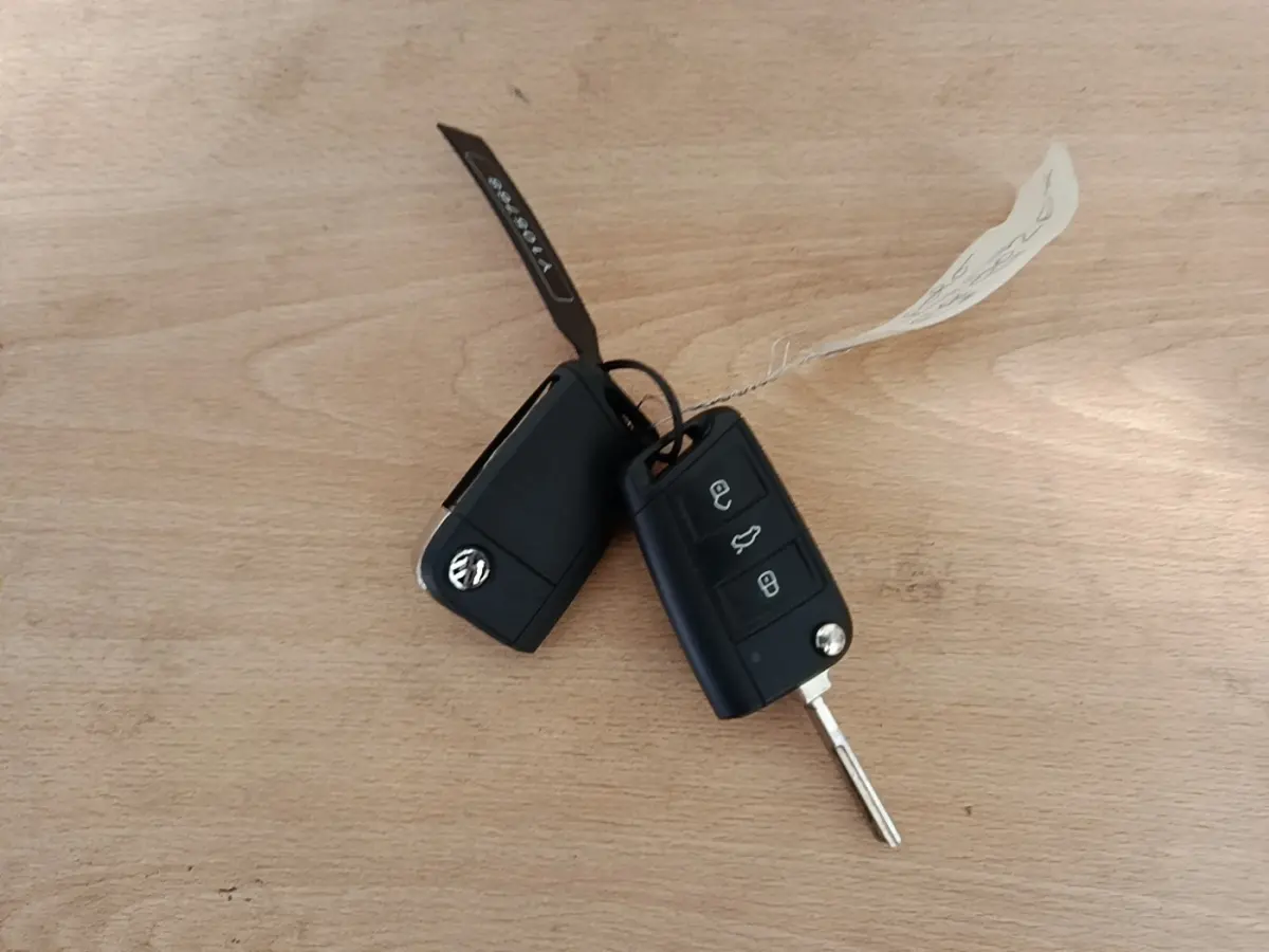 Clés noires Volkswagen Polo 1.0 TSI 115 DSG7 Carat posées sur une surface en bois clair.