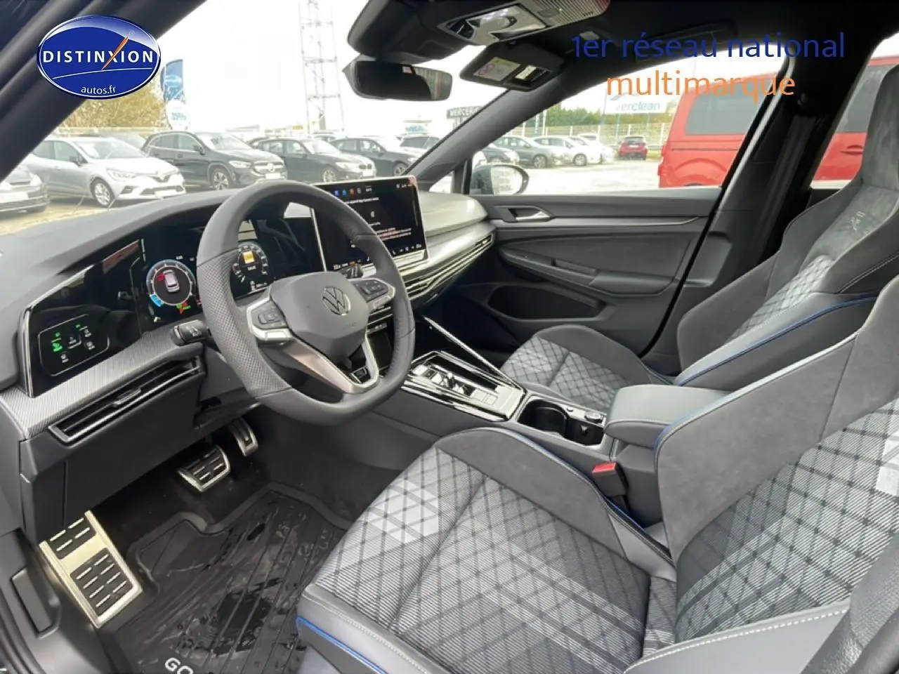 Vue intérieure côté conducteur de la Volkswagen Golf 2026, sièges tissu gris à motifs et volant cuir multifonction.
