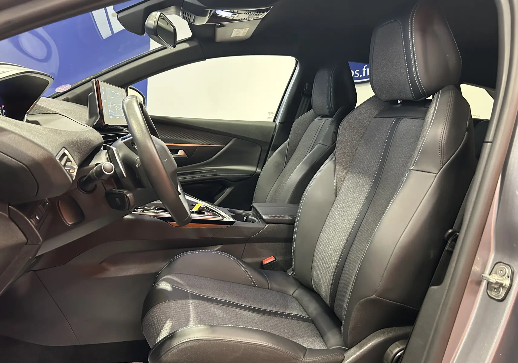 Vue intérieure côté conducteur du Peugeot 3008 gris 2024, avec sièges cuir et tissu, volant multifonction et écran GPS intégré.