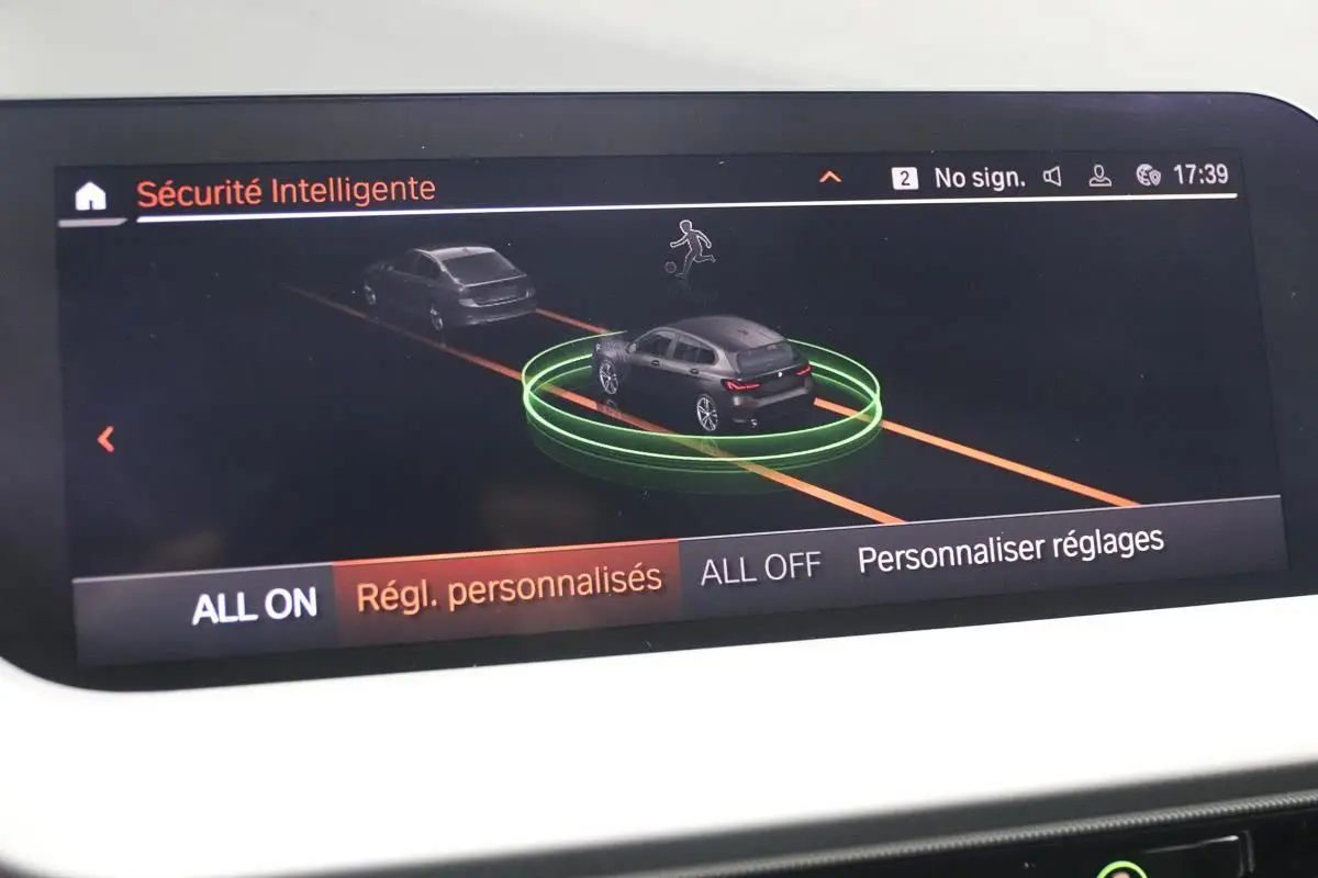 Écran de la BMW Série 1 noire 116d 2023 montrant l'interface de sécurité intelligente avec vue 3D du véhicule en circulation.