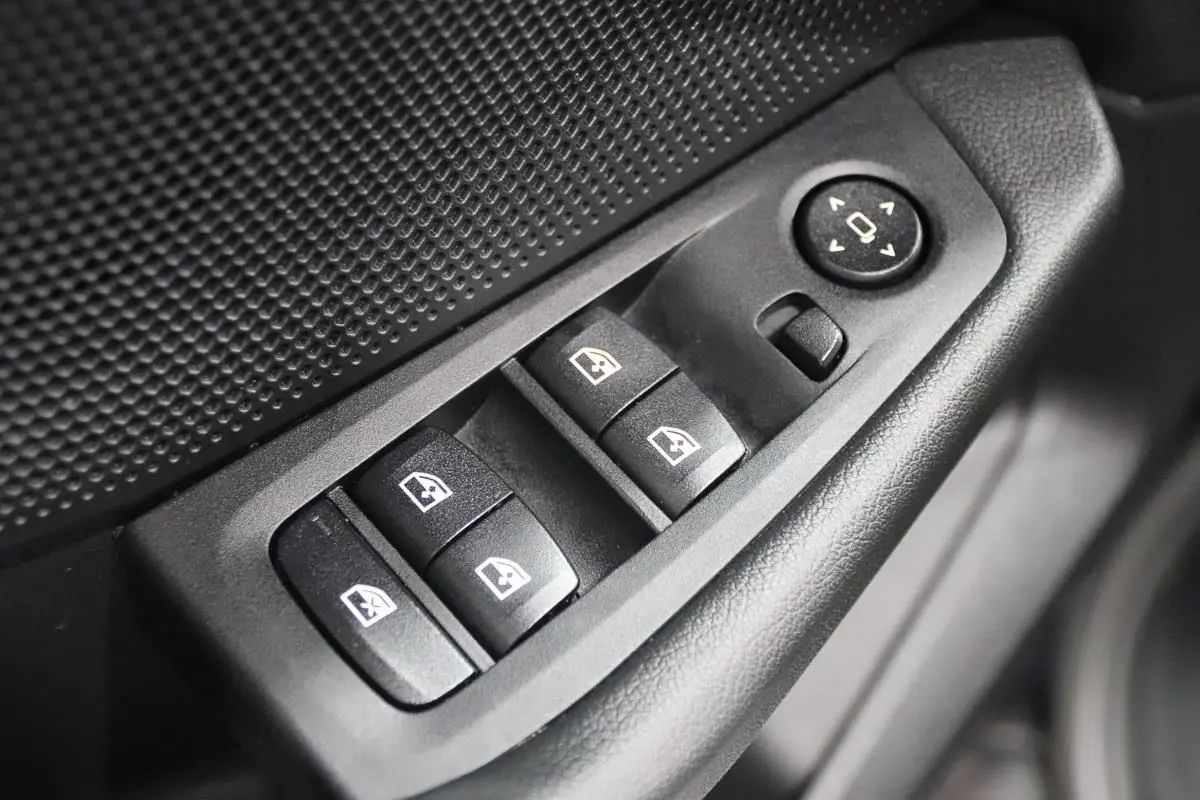 Gros plan sur les commandes de lève-vitres et réglage des rétroviseurs côté conducteur d'une BMW Série 1 noire.