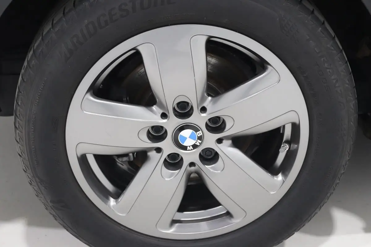 Gros plan sur la jante alliage argentée avec logo BMW au centre d’une BMW Série 1 noire.