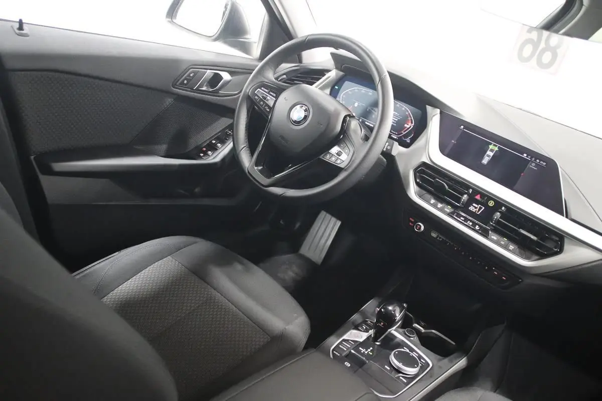 Vue intérieure côté conducteur de la BMW Série 1 116d noire, avec tableau de bord digital et écran central GPS.