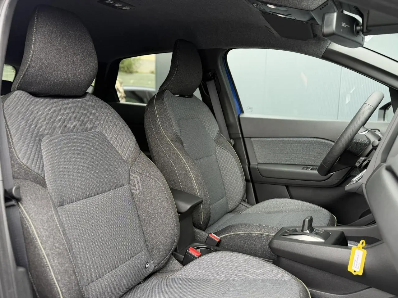 Vue intérieure côté droit du Renault Captur 2026, sièges tissu gris avec console centrale et volant visible.