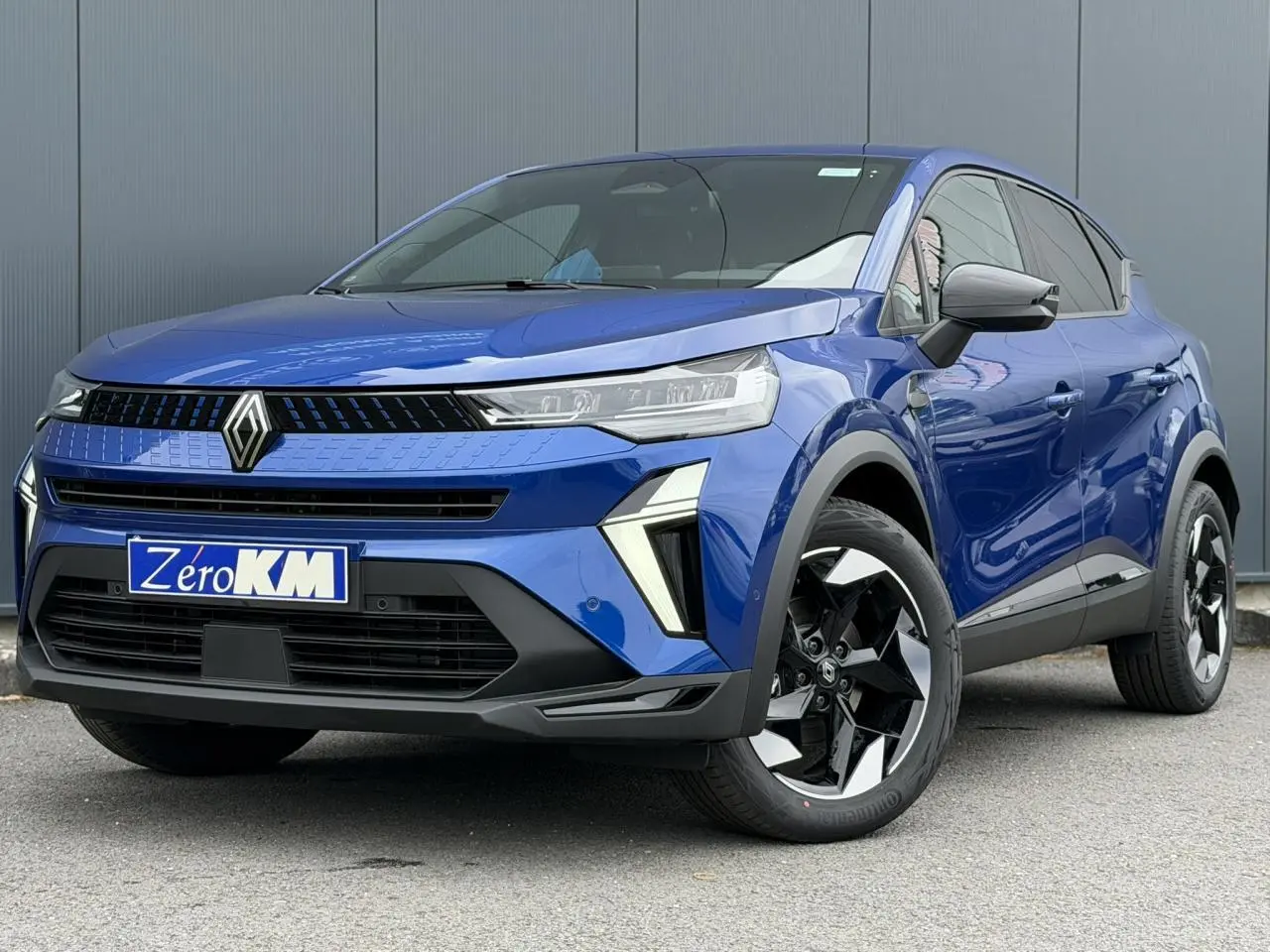 Vue 3/4 avant droite du Renault Captur 2026 bleu Iron avec jantes aluminium 18 pouces et calandre noire brillante.