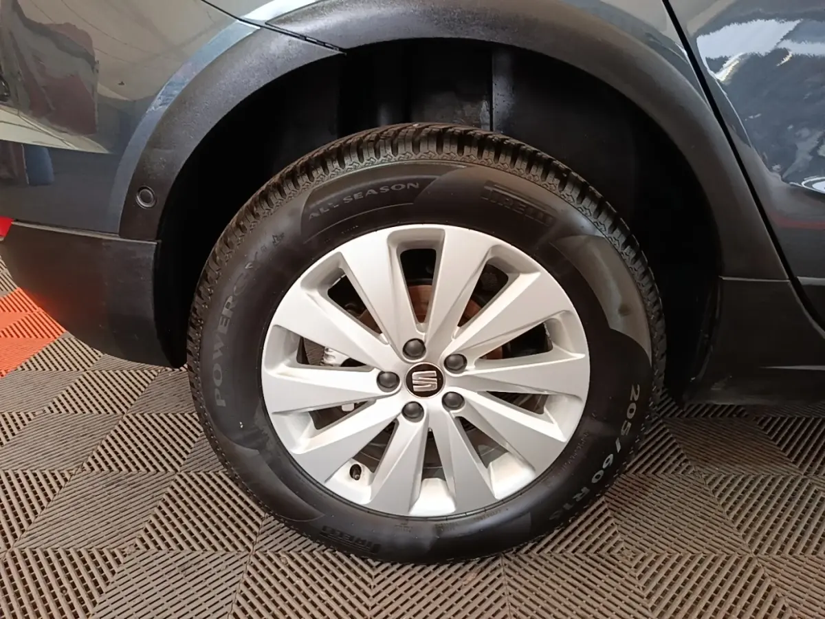 Gros plan sur la roue avant droite d’un SEAT Arona gris clair avec jante alliage et pneu Pirelli all season.
