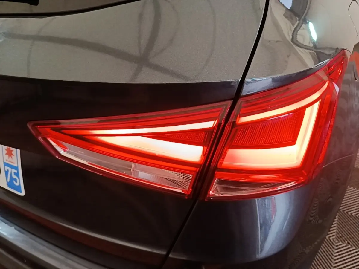 Gros plan sur le feu arrière droit rouge d’un SEAT Arona gris clair, avec une partie de la plaque d’immatriculation visible.