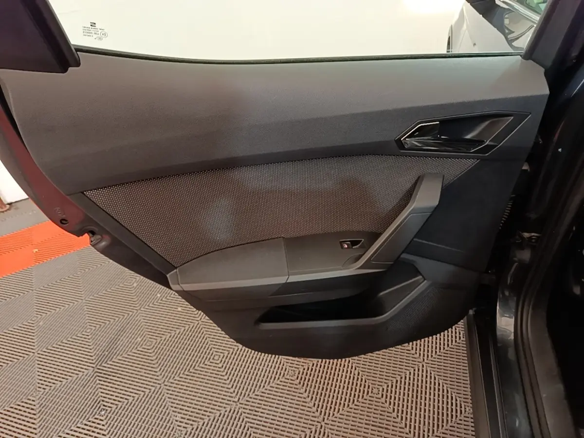 Détail de la porte intérieure côté droit d'une SEAT Arona gris clair, avec poignée et commande de vitre.