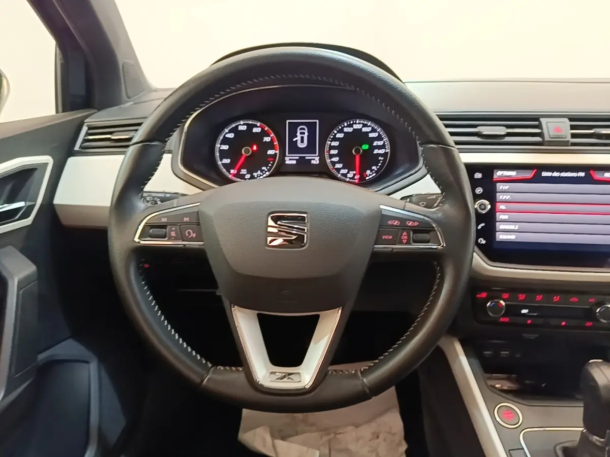 Vue centrée sur le volant en cuir noir d'une SEAT Arona 2019, avec tableau de bord et écran tactile visibles.