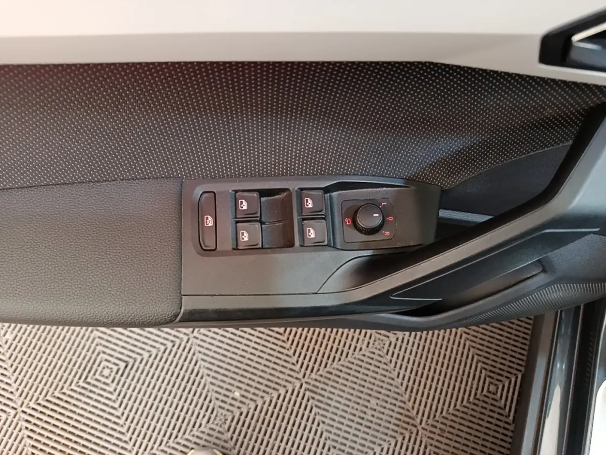 Gros plan sur la commande des vitres et rétroviseurs côté conducteur d’une SEAT Arona gris clair, intérieur noir.