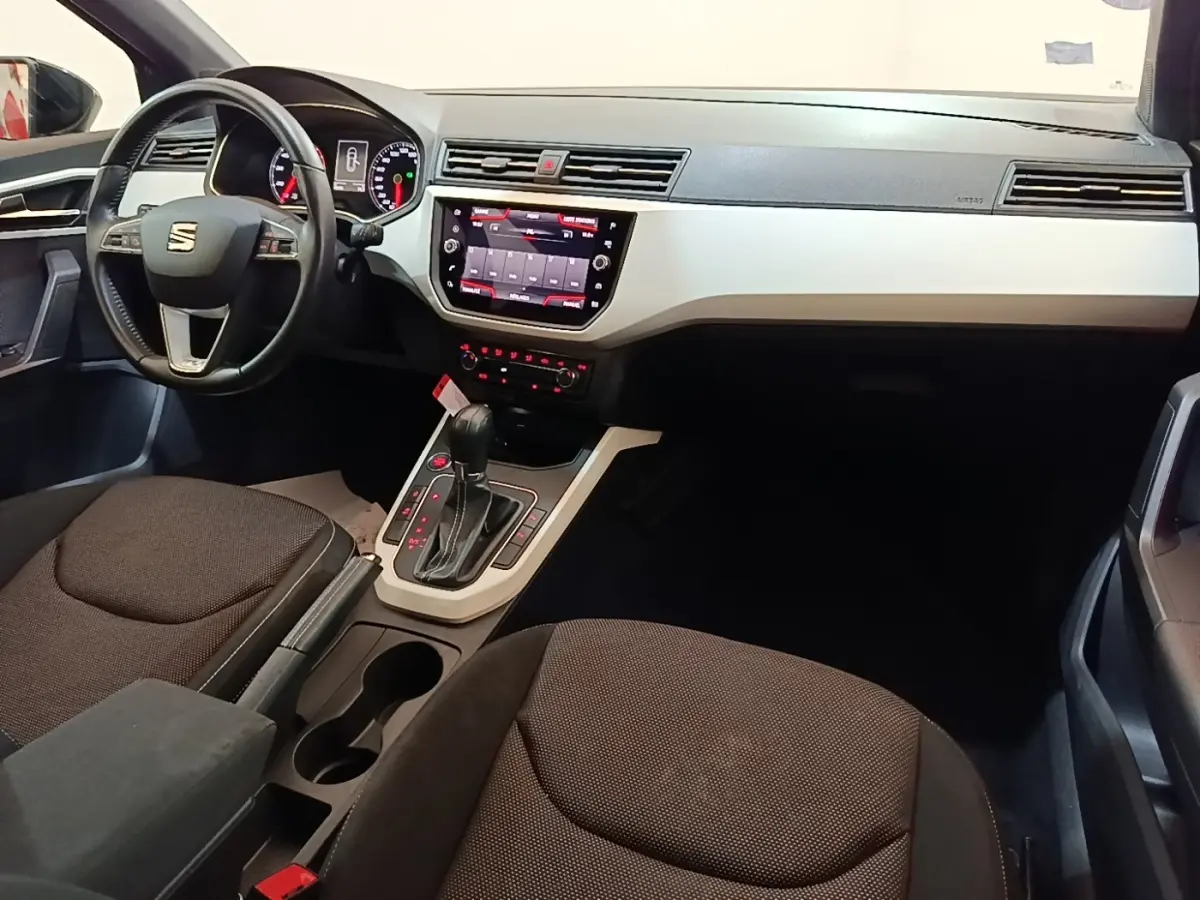 Vue intérieure avant droite du tableau de bord et console centrale du SEAT Arona gris clair avec écran tactile et volant multifonctions.