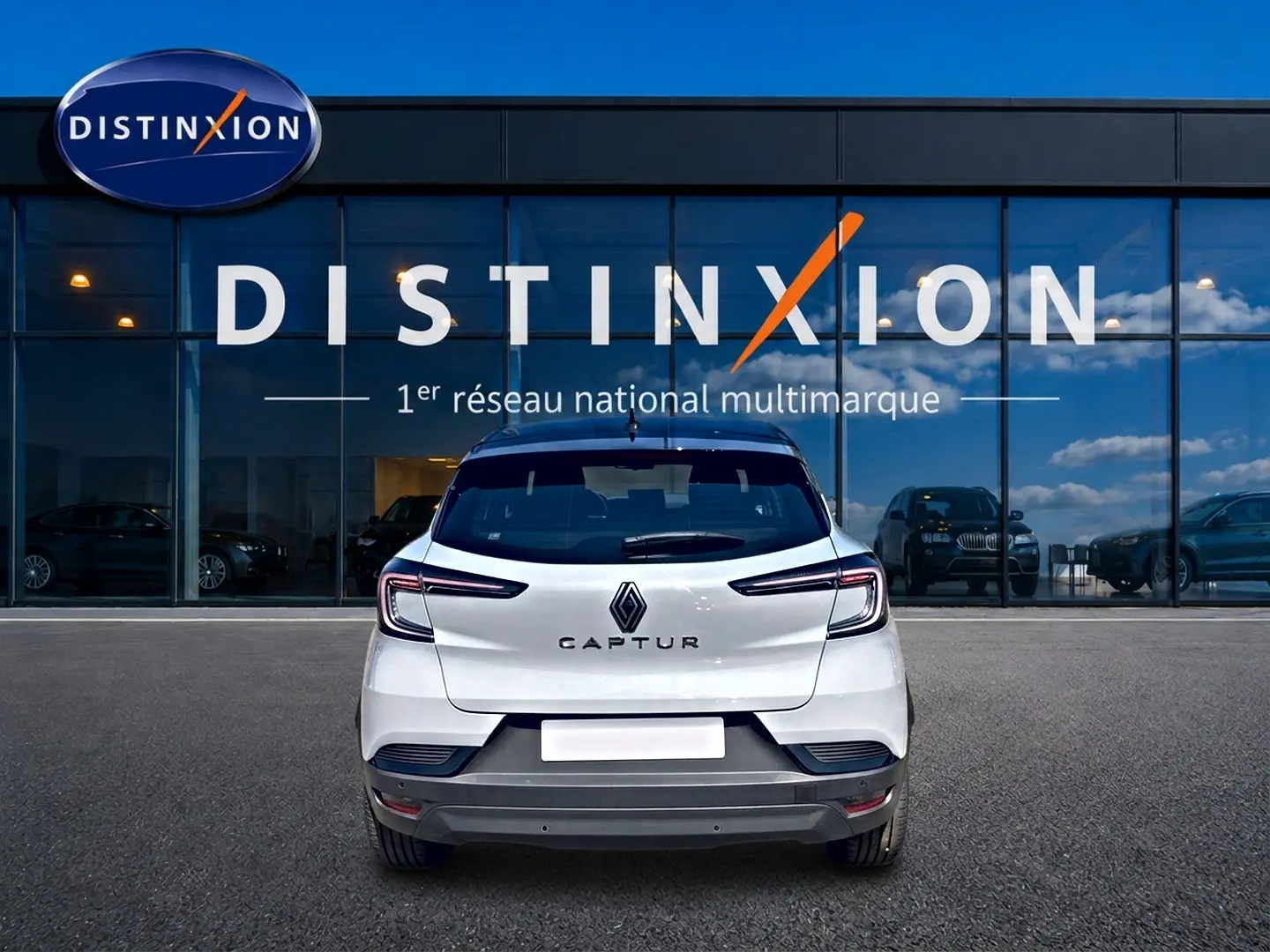 Vue arrière d'un Renault Captur blanc avec toit noir, garé devant une vitrine Distinxion.