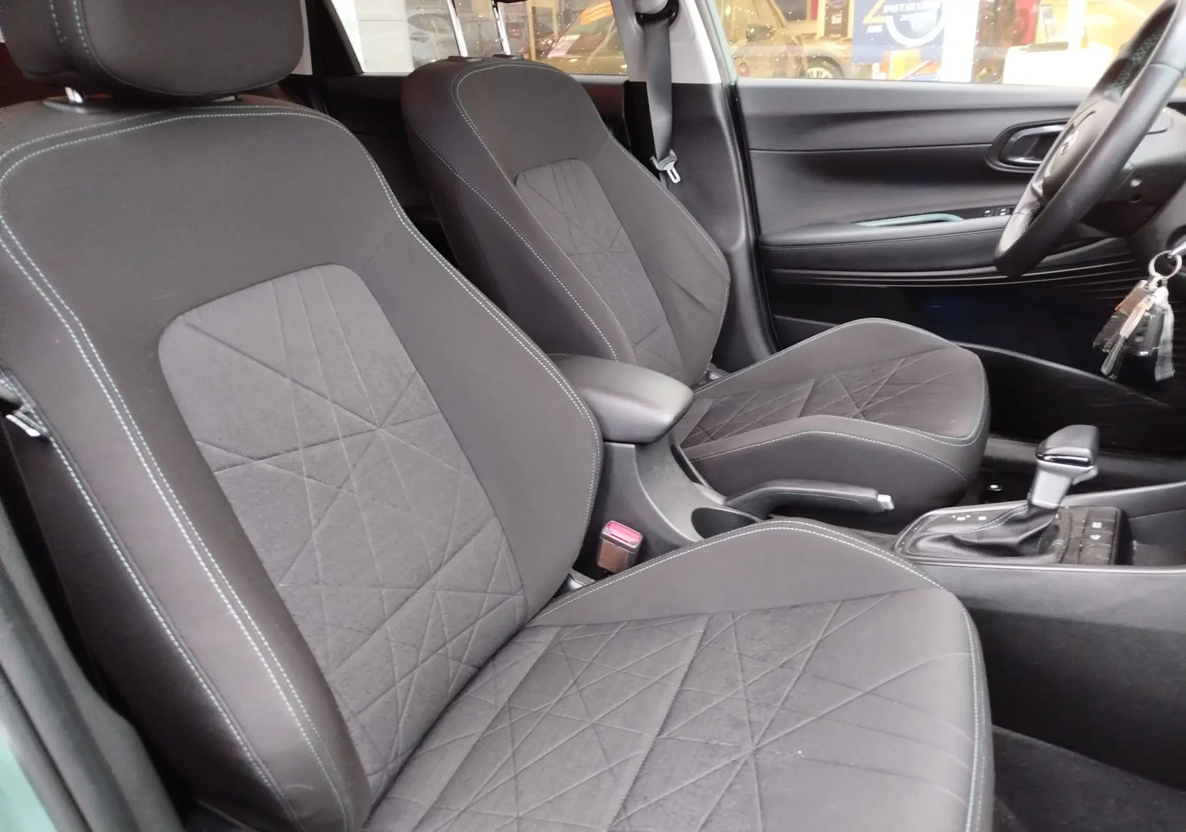 Vue intérieure côté droit montrant les sièges avant noirs avec surpiqûres et la console centrale d'une Hyundai Bayon 2022.