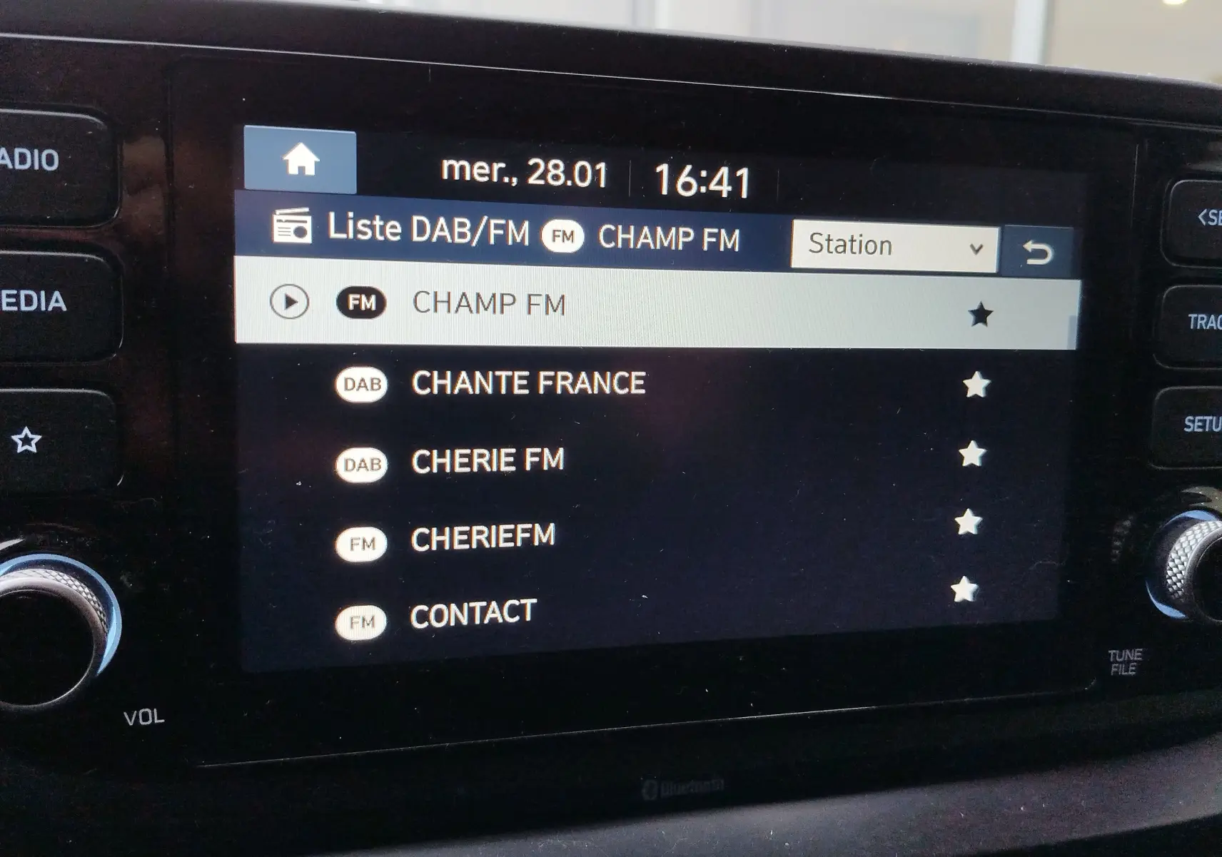 Écran central tactile du Hyundai Bayon 2022 montrant la liste des stations radio DAB/FM avec interface noire et boutons latéraux.