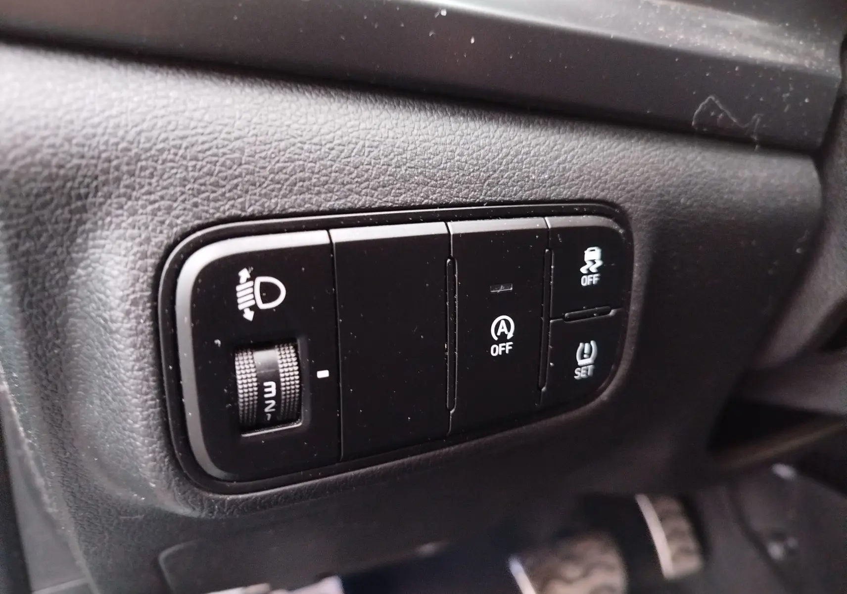 Gros plan sur les commandes noires du tableau de bord côté gauche du Hyundai Bayon 2022, avec réglage des phares et fonctions assistées.