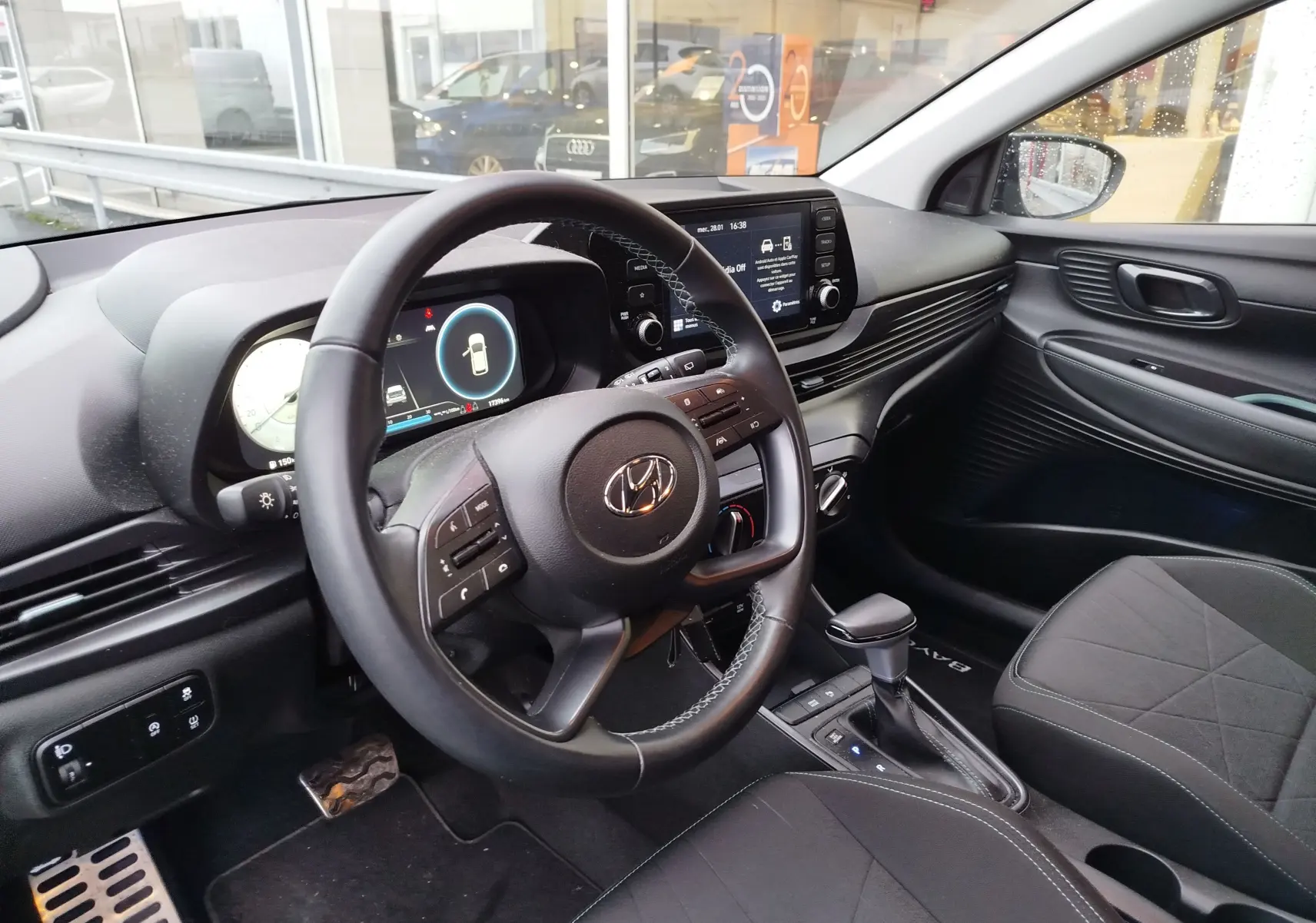 Vue intérieure côté conducteur de la Hyundai Bayon 2022, tableau de bord moderne avec écran tactile et volant multifonction noir.