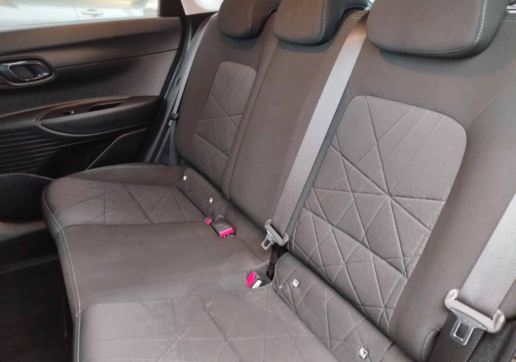 Vue intérieure côté gauche des sièges arrière noirs avec surpiqûres en losange du Hyundai Bayon 2022.