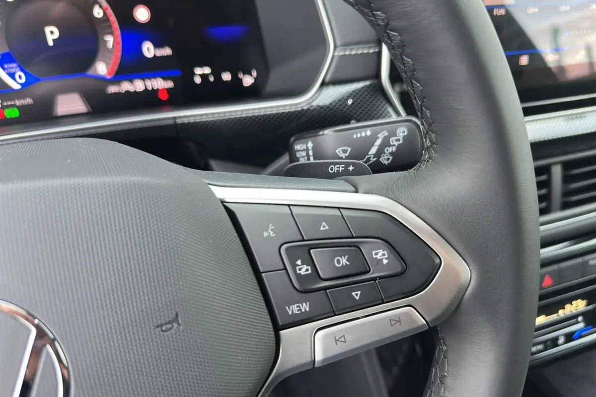 Gros plan sur le volant cuir multifonctions et le tableau de bord numérique du Volkswagen T-Cross TSI 116 DSG7 R-Line 2025.