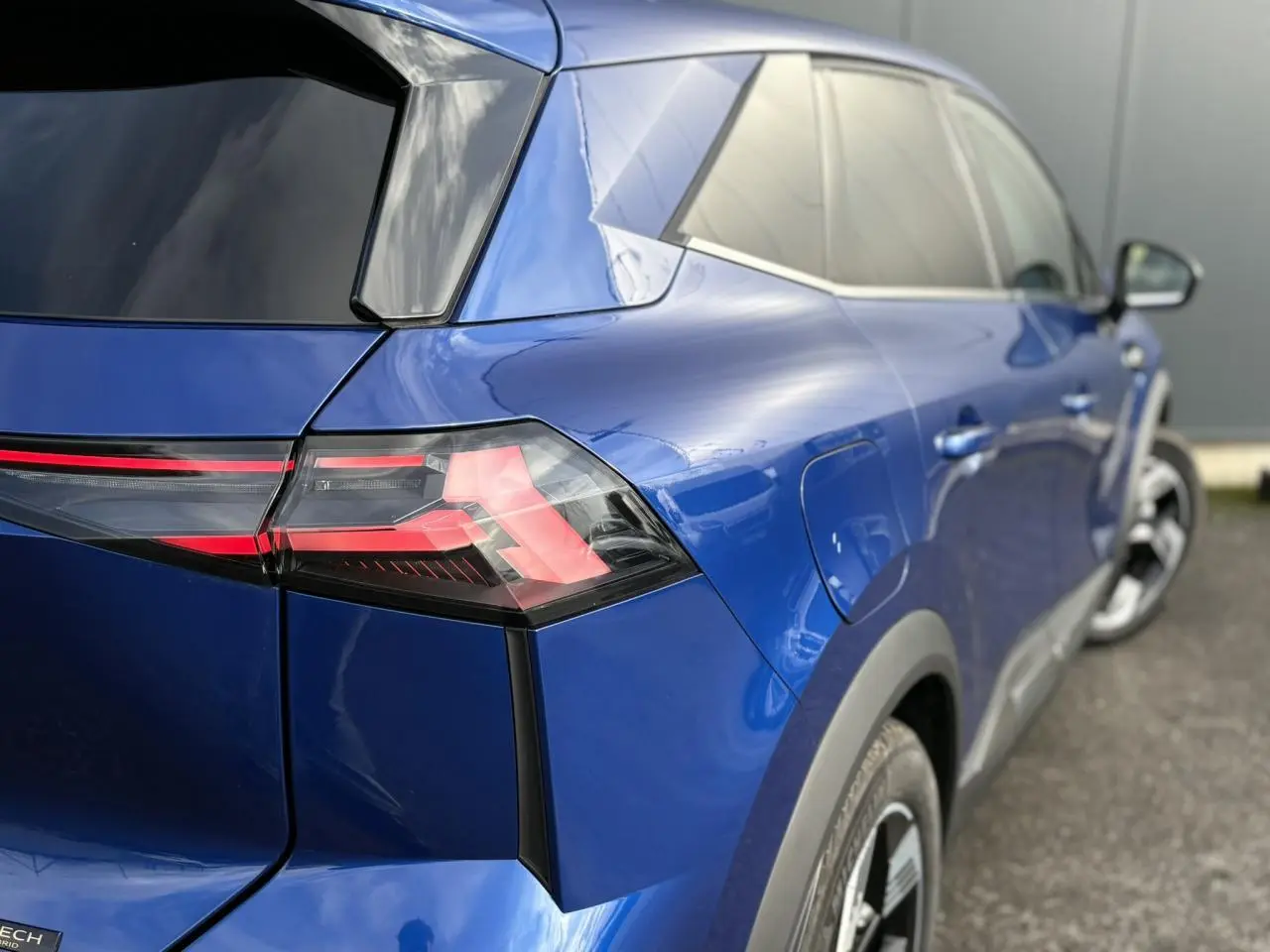 Vue 3/4 arrière droite sur Renault SYMBIOZ bleu Iron, mettant en valeur les feux LED et la carrosserie brillante.