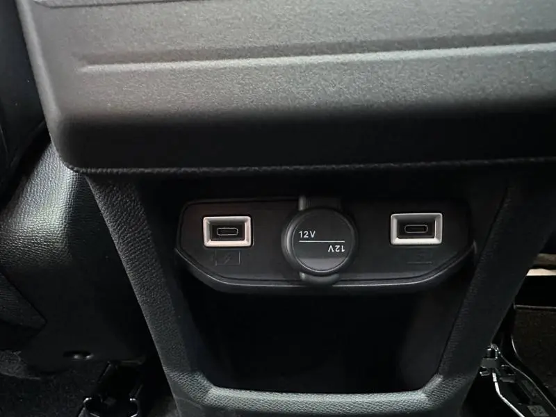 Gros plan sur la prise 12V et deux ports USB situés sous l'accoudoir central du Citroën C5 Aircross gris Platinium.