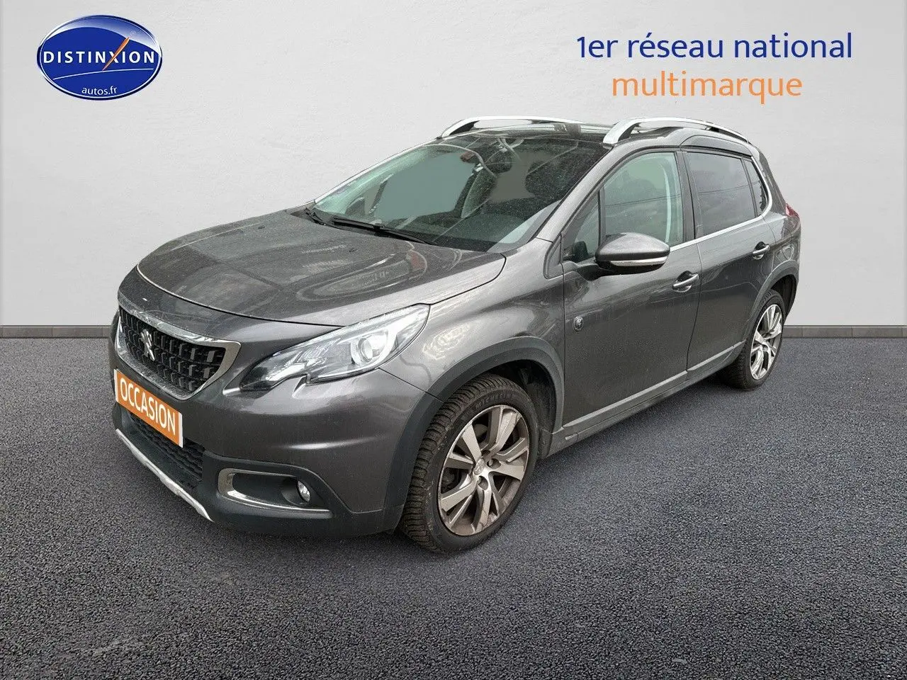 Peugeot 2008 gris platinium en 3/4 avant droit, avec jantes alliage et barres de toit visibles.