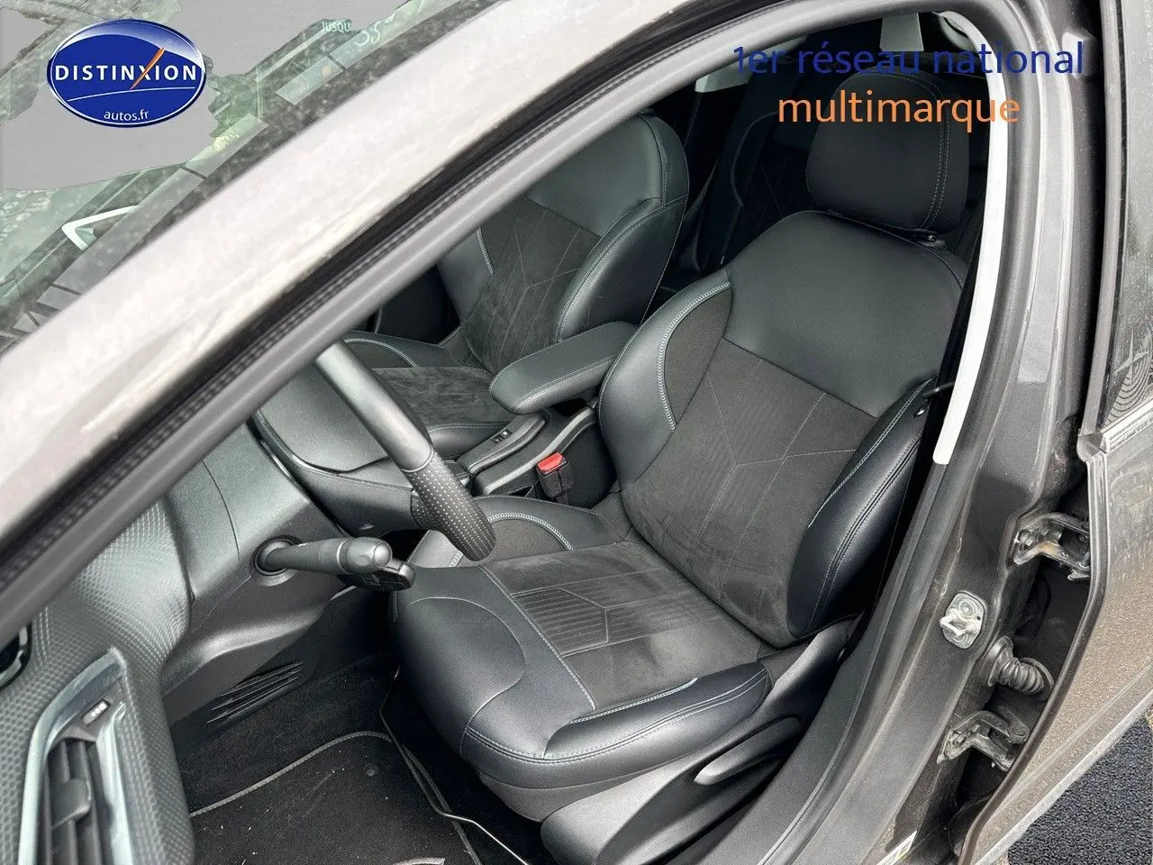 Vue intérieure côté conducteur d'un Peugeot 2008 gris platinium, sièges en cuir noir avec surpiqûres grises.