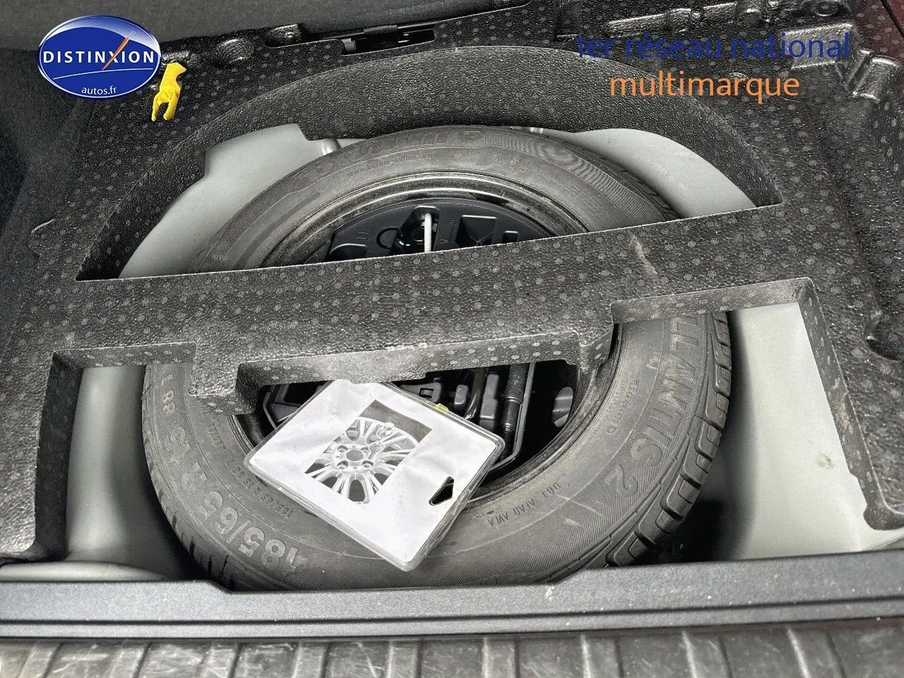 Vue en plongée sur la roue de secours et le rangement en mousse dans le coffre du Peugeot 2008 gris platinium.