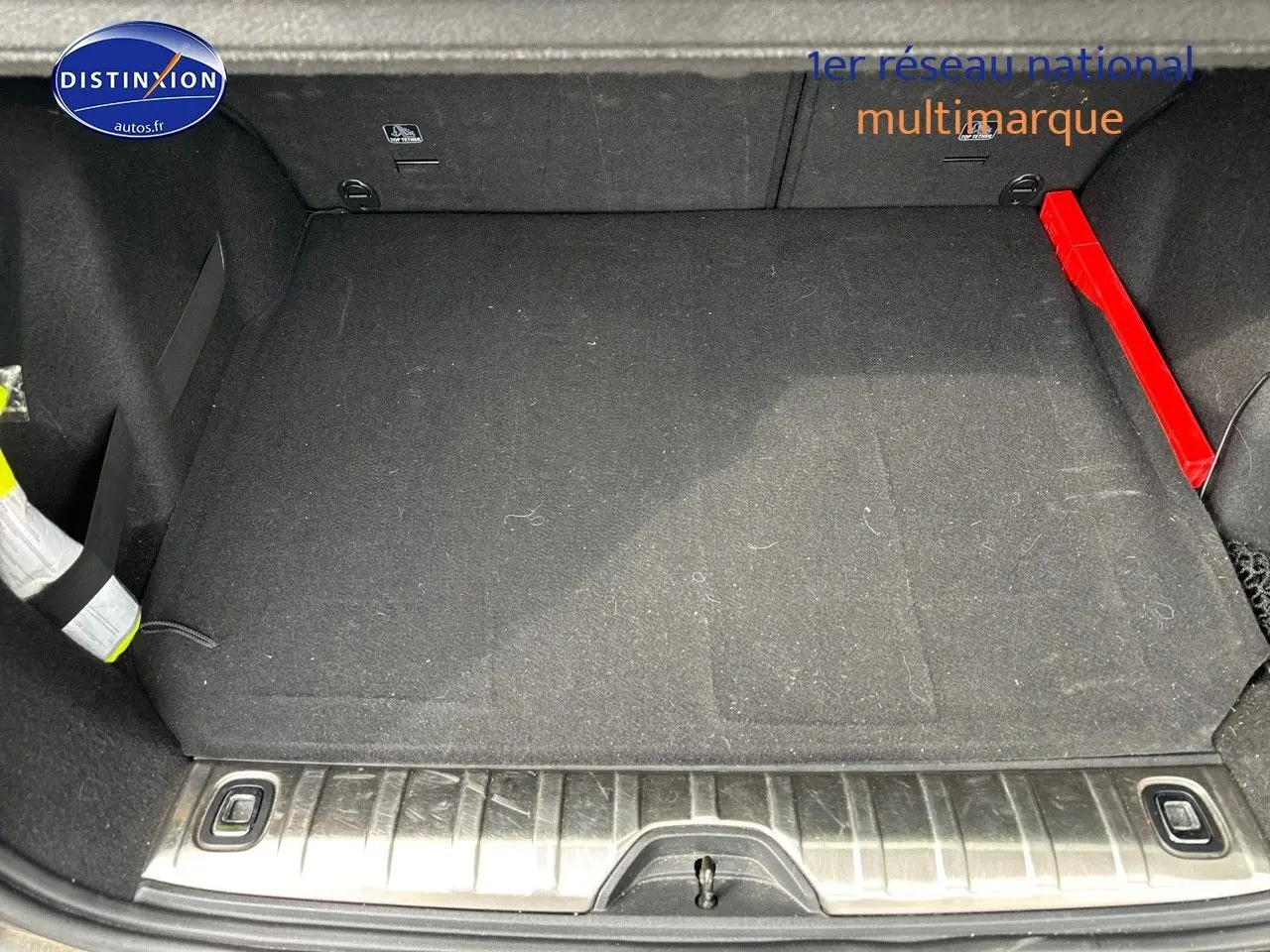 Coffre ouvert du Peugeot 2008 gris platinium, vue plongeante sur le tapis noir et seuil de chargement métallique.