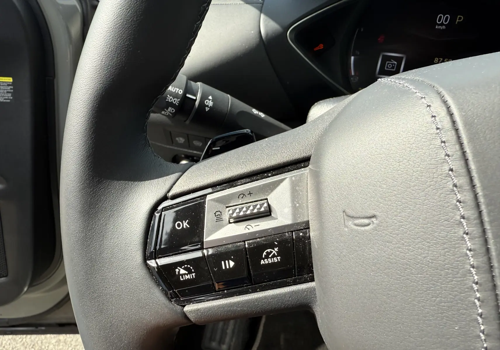 Gros plan sur le volant gris du DS3 2024 avec commandes multifonctions et tableau de bord partiellement visible.