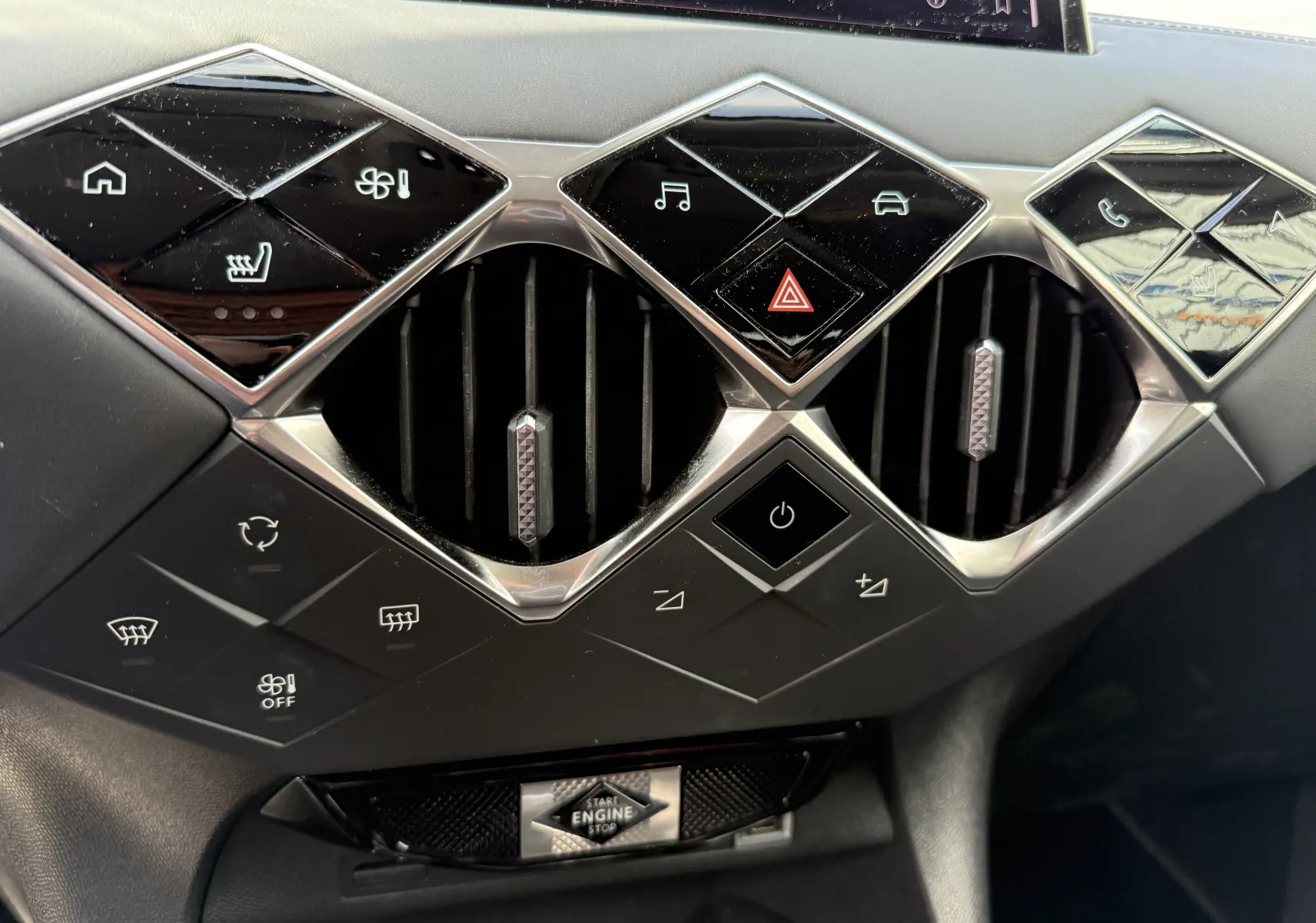 Détail du tableau de bord du DS3 2024 gris laqué, mettant en valeur les commandes tactiles et les aérateurs au design géométrique.