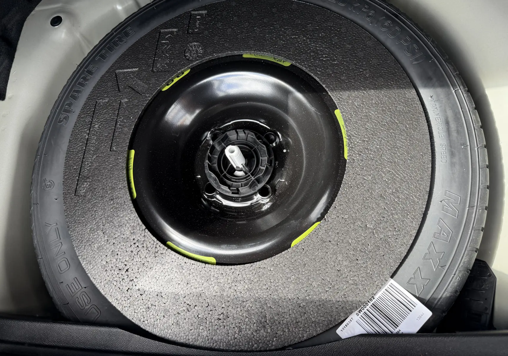 Gros plan sur la roue de secours noire du coffre d'une DS3 2024 gris laqué toit noir, version BlueHDi 130 EAT8 Opera.