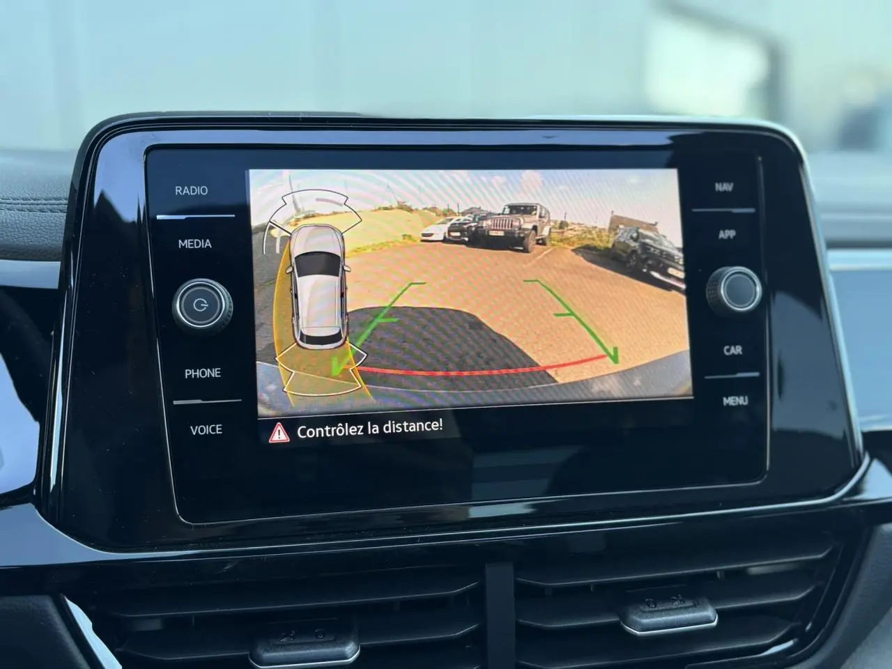 Écran tactile intérieur affichant la caméra de recul du Volkswagen T-Roc gris Indium avec alertes de distance.