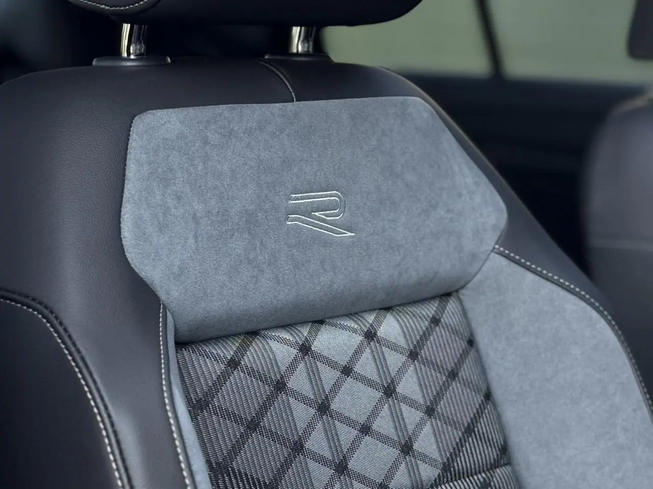 Gros plan sur le siège avant gris et noir du Volkswagen T-Roc 2025 avec logo R-Line brodé sur l'appuie-tête.