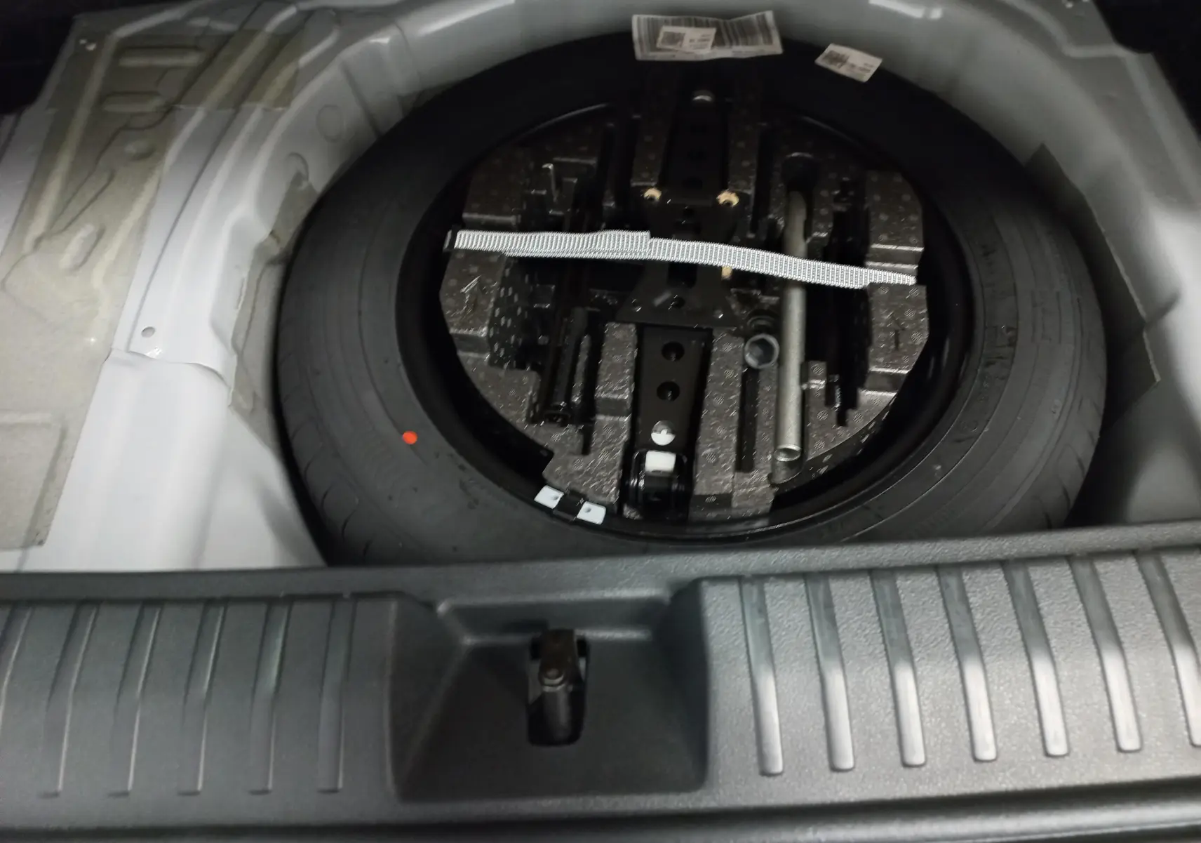 Gros plan sur la roue de secours et le double plancher du coffre du Skoda Kamiq 2025 Blanc Lune Monte-Carlo.