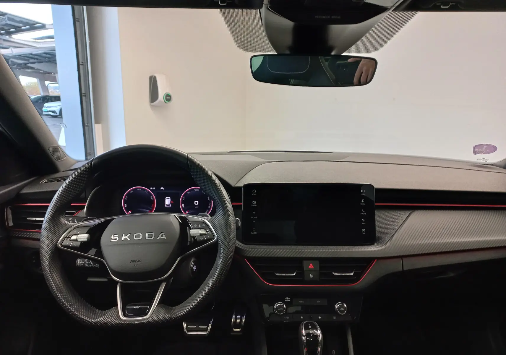Intérieur du Skoda Kamiq 2025 vu de face, tableau de bord noir avec éclairage rouge et volant multifonction marqué SKODA.