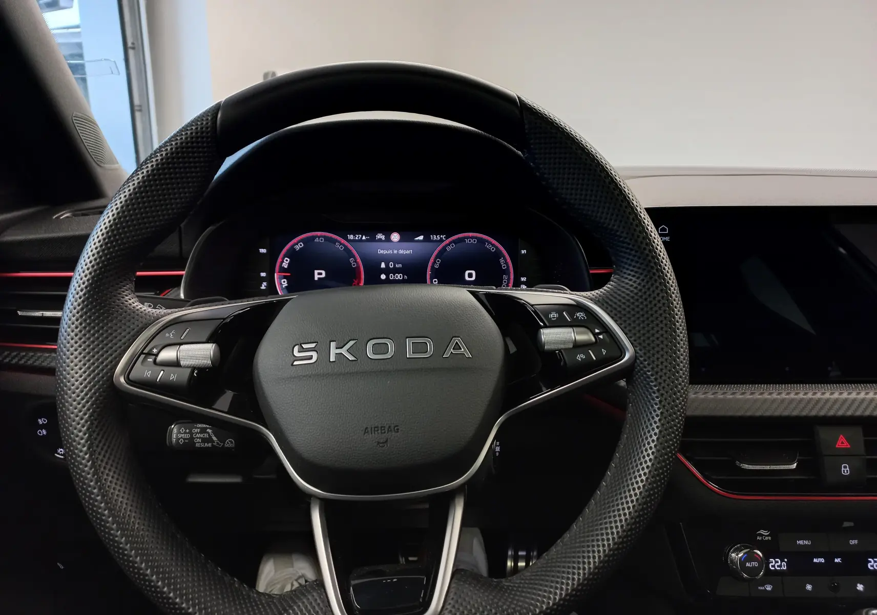 Vue centrée sur le volant perforé SKODA du KAMIQ 2025 avec tableau de bord numérique et détails intérieurs noirs et rouges.
