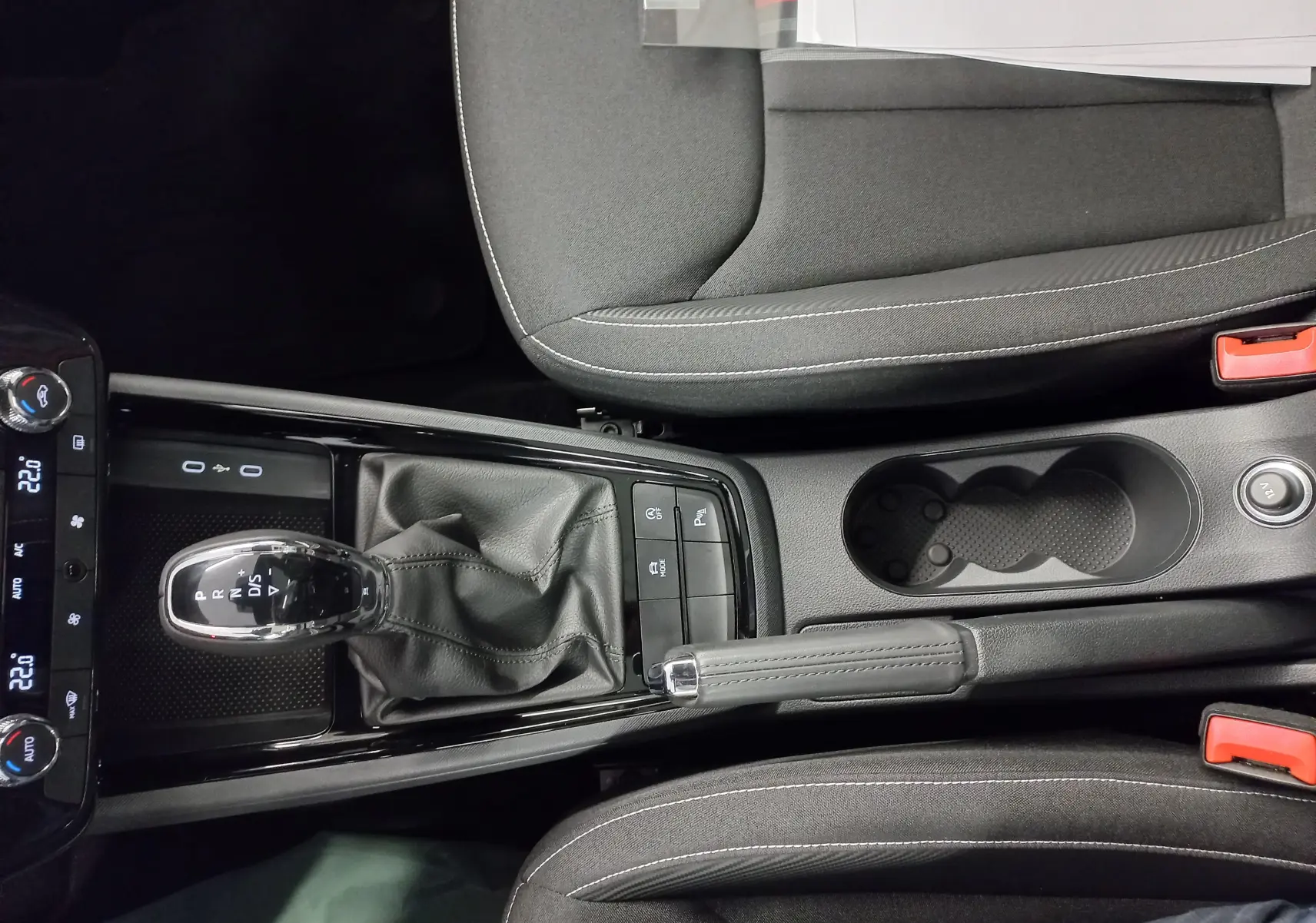 Vue plongeante sur la console centrale du Skoda Kamiq 2025 avec levier de vitesses DSG et frein à main manuel.