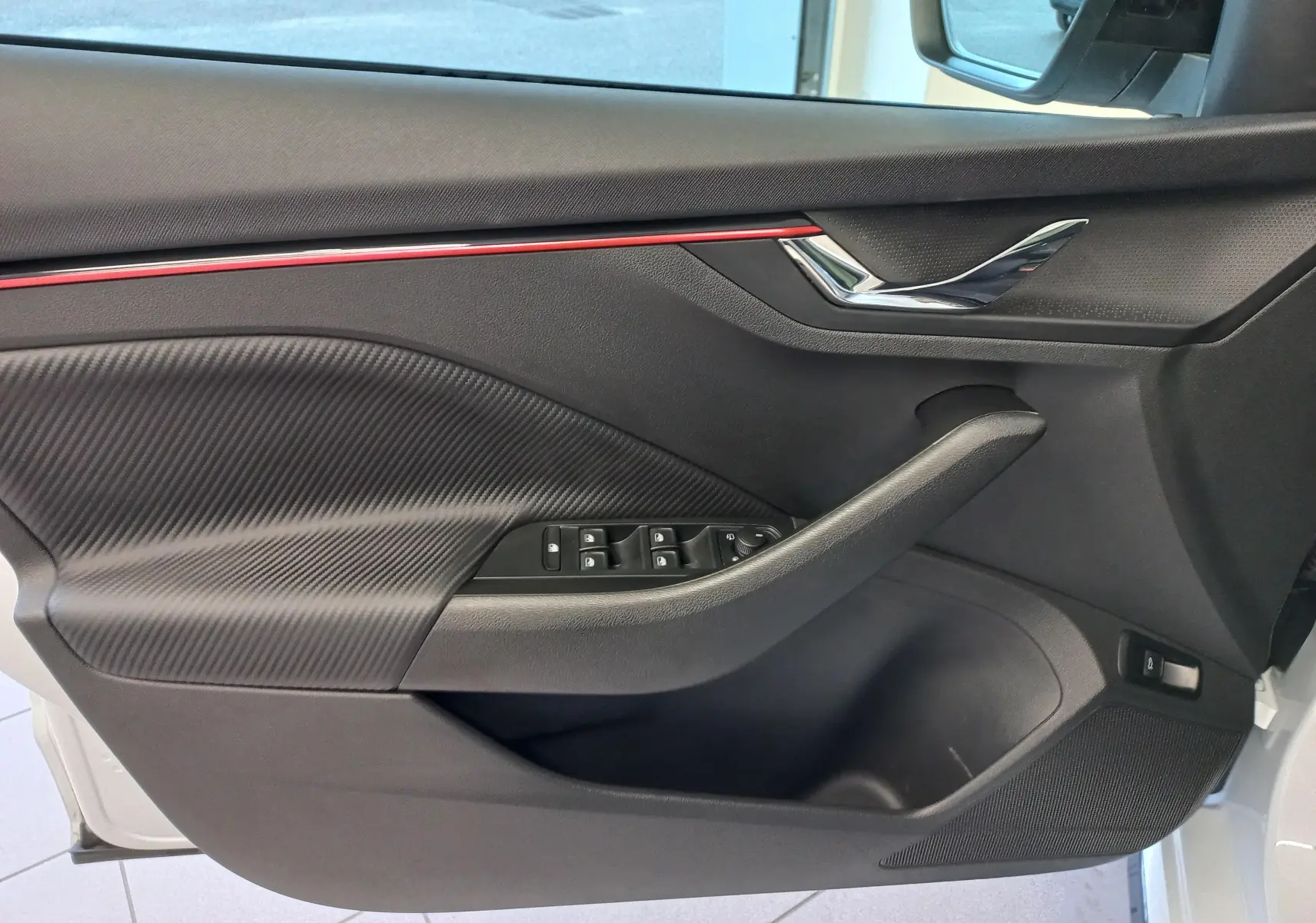 Intérieur côté gauche de la porte d'une Skoda Kamiq 2025 Monte-Carlo, avec garniture noire et bande rouge décorative.