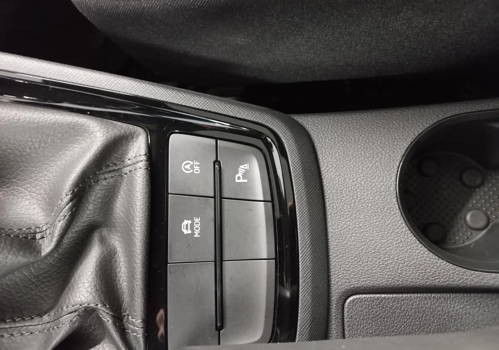 Gros plan sur la console centrale du Skoda Kamiq blanc, montrant les boutons de mode, arrêt auto et aide au stationnement.