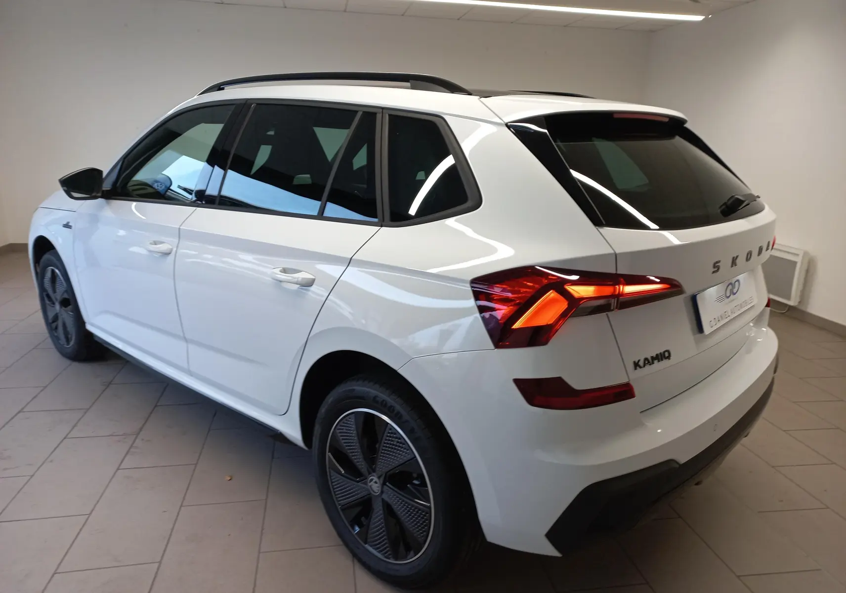 Vue 3/4 arrière droite du Skoda Kamiq 2025 blanc Lune avec feux allumés et jantes noires distinctives Monte-Carlo.