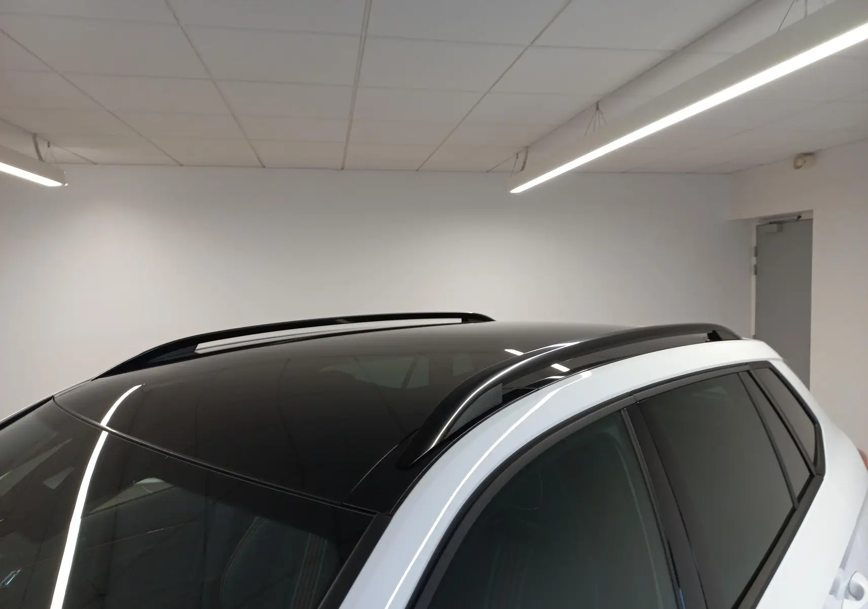 Toit panoramique noir et barres de toit noires sur le côté droit d’un Skoda Kamiq Blanc Lune 2025.