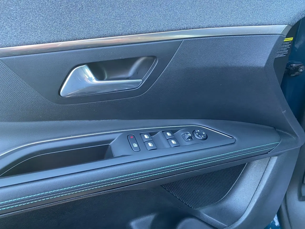 Vue rapprochée de la porte avant gauche du Peugeot 3008 Bleu Celebes, montrant les commandes des vitres et le décor avec surpiqûres bleues.